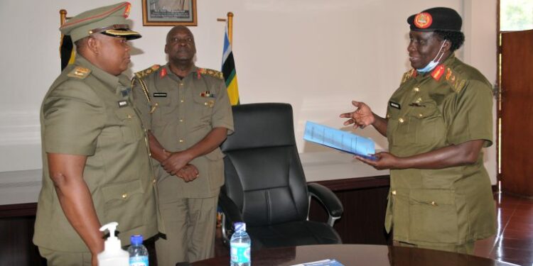 Brig Gen Agnes Musoke (R) preparing to handover instruments of office to Lt Col Betty Musuya (L) as Brig Gen Ssebugwawo (C) Looks on.