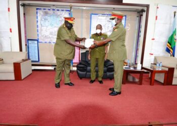 Gen Wilson Mbadi looks on as Lt Gen Andrew Gutti (L) handsover a report to Maj Gen Igumba