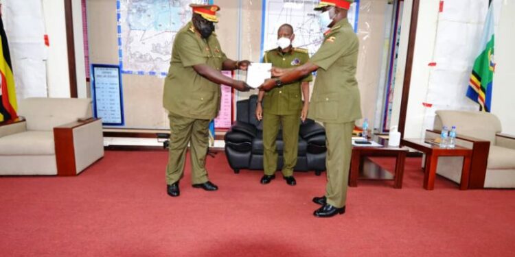 Gen Wilson Mbadi looks on as Lt Gen Andrew Gutti (L) handsover a report to Maj Gen Igumba