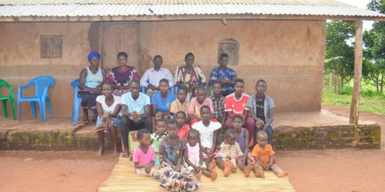 Birungi Malirweki, 56 (2nd from the right in the back row) and her family at their home in Nyakatehe 2 village, Kyangwali Sub County in Kikuube District, South Western Uganda.