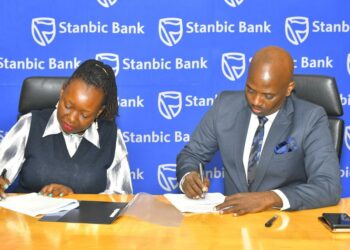 Stanbic Bank Executive Director Emma Mugisha with Victoria University Vice Chancellor Dr Muganga signing the deal