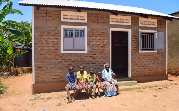 PHOTO: Jesca Magemeso, 58, poses for a family portrait with members of her household in front of their home in Buwaiswa Village, Buwaaya Sub- County, Mayuge District