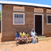 PHOTO: Jesca Magemeso, 58, poses for a family portrait with members of her household in front of their home in Buwaiswa Village, Buwaaya Sub- County, Mayuge District