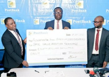 John Walugembe ED Federation of Small and Medium Enterprise (FSME) recieves a cheque from Julius Kakeeto the CEO Post Bank flanked by the Bank's ED Andrew Kabeera. The money is geared towards training and  empowering SME agri-businesses.