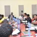 Ministers Tom Butime ( extreme far right with grey hair) and Peace Mutuuzo (in white) perusing through documents at the meeting with the committee