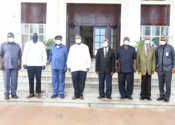 Col. Tom Butime (in black) standing next to President Yoweri Museveni at State House