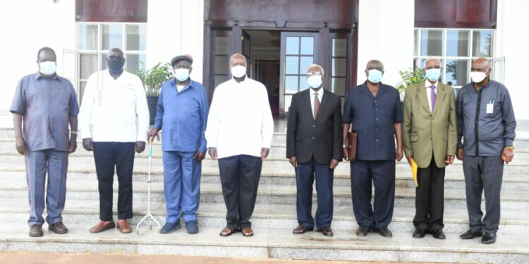 Col. Tom Butime (in black) standing next to President Yoweri Museveni at State House