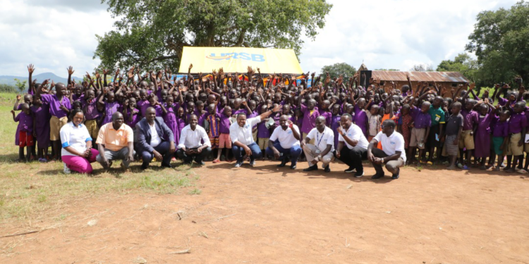 Pupils of Oleni Primary School in a group photo with URSB staff and Partners during the handover of the health and sanitation facility.