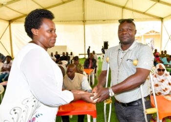 State House Comptroller Jane Barekye hands over President Museveni's cash contribution to Fred Katongole a Police driver and survivor of the November 2021 bomb attacks near CPS Kampala. PPU Photo