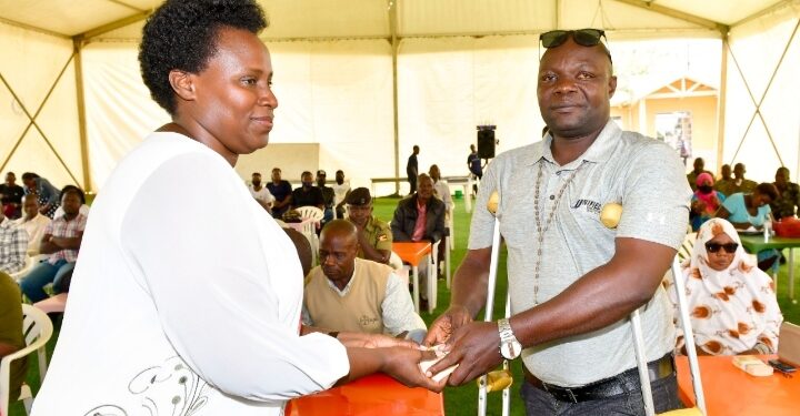 State House Comptroller Jane Barekye hands over President Museveni's cash contribution to Fred Katongole a Police driver and survivor of the November 2021 bomb attacks near CPS Kampala. PPU Photo