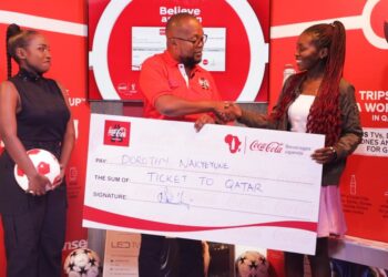 Newton Lee Ogong Chanels & Trade Marketing Manager Coca-Cola Beverages Uganda handing over the dummy ticket to the first Ticket winner Dorothy Nakyeyune