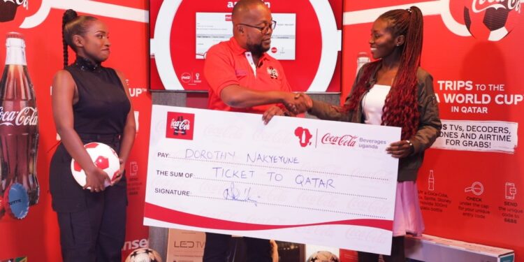 Newton Lee Ogong Chanels & Trade Marketing Manager Coca-Cola Beverages Uganda handing over the dummy ticket to the first Ticket winner Dorothy Nakyeyune
