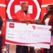 Newton Lee Ogong Chanels & Trade Marketing Manager Coca-Cola Beverages Uganda handing over the dummy ticket to the first Ticket winner Dorothy Nakyeyune