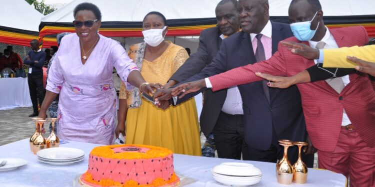 Hon. Babalanda joined by other government officials to cut a cake during the official opening of Bushenyi RDC Office