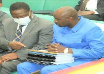 Hon. John Bosco Ikojo (R) confering with Minister David Bahati prior to his presentation of the committee report on the electricity loan