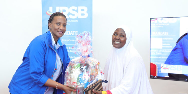 Freda Bwiizi, Director Research & Planning hands over a gift hamper to Faridah Asiimwe of UWEAL during the closure of URSB's Customer Engagement Week.