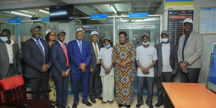 Vice President Jessica Alupo (centre) with Post Bank ED Andrew Kabeera second left, Ministers Amos Lugolobi and Raphael Magyezi plus some of the PDM beneficiaries and Coordinator Dennis Galabuzi extreme right after the first recipeints got their PDM cash at Post Bank Kayunga Branch