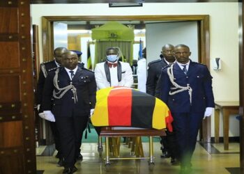 Police pallbearers wheel the body of late Okabe out of the Chamber after the sitting that honoured him