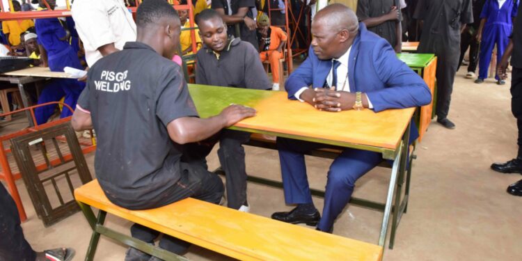 Minister of State for Kampala Capital City and Metropolitan Affairs Kyofatogabye Kabuye tries out  furniture made by the welding students as they have a chat during the Presidential Initiative on skilling the Girl/Boy Child project 7th intake inspection of the skills of the students as they show case their work at Wabigabo Centre on 15th February 2023. Photo by PPU/Tony Rujuta.