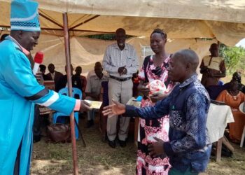 The Won Nyaci hands over soccer balls to different group leaders at Obot Primary School, Iceme sub county in Oyam District.