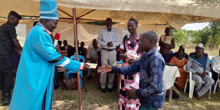 The Won Nyaci hands over soccer balls to different group leaders at Obot Primary School, Iceme sub county in Oyam District.