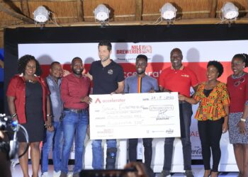 Nile Breweries Ltd MD Mr Adu Rando (4th Left) displays a dummy cheque after placing signature during the Accelerator Program launch event for Cohort 2023 at NBL Head Offices in Luzira.