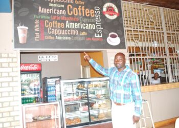 Charles Kirumira, the manager, Highway- Masaka, pointing at some of the drinks always asked for by customers. PHOTO BY BRIAN MUGENYI