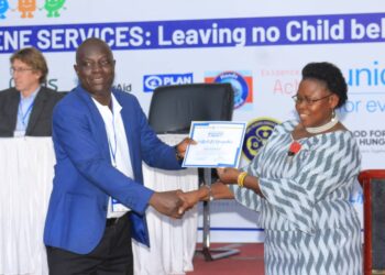 Hon. Joyce Moriku Kaduchu delivers a certificate of appreciation to Mr. Charles Opolot, the Executive Director for HAI Agency (U) Ltd, in appreciation of his efforts in leading the campaign on Wash in schools.