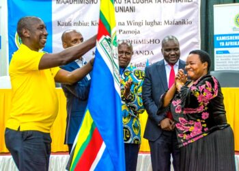 Prime Minister Robinah Nabbanja (Right) handing over EAC Flag to Rwandan Representative at the Conclusion of World Kiswahili Day in Kampala