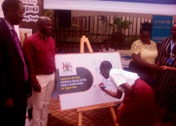 Minister of State for Sports Peter Ogwang(2nd Left) witnesses a girl child signing on a placard to launch Educate Her campaign at the Ministry of Education and Sports on Embassy House in Kampala on Friday