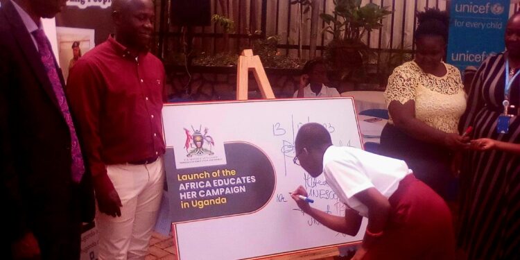 Minister of State for Sports Peter Ogwang(2nd Left) witnesses a girl child signing on a placard to launch Educate Her campaign at the Ministry of Education and Sports on Embassy House in Kampala on Friday