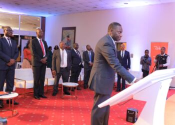Deputy Governor Bank of Uganda Dr. Michael Atingi Ego launches the Wendi Mobile Wallet by having his finger prints verified on the system as Post Bank MD Julius Kakeeto, Wilbrod Owor the UBA Executive Director and other Bank CEOs look on in the background