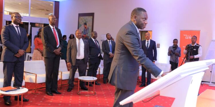 Deputy Governor Bank of Uganda Dr. Michael Atingi Ego launches the Wendi Mobile Wallet by having his finger prints verified on the system as Post Bank MD Julius Kakeeto, Wilbrod Owor the UBA Executive Director and other Bank CEOs look on in the background