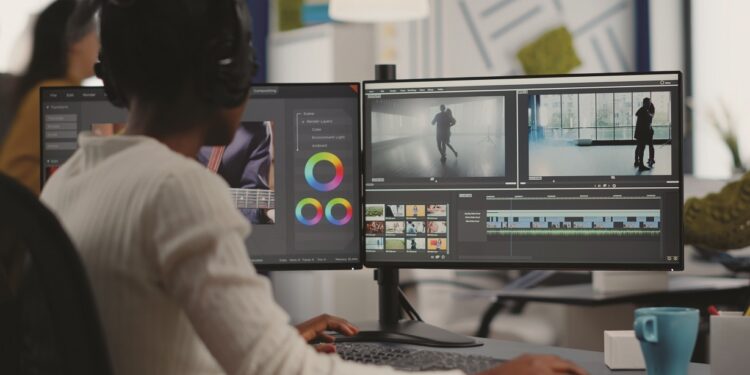 African video editor working with footage and sound, editing new project cutting film montage sitting in modern agency office. Woman using computer processing movie in post production software