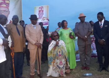 The Won Nyaci- elect HRH Eng Dr Michael Moses Odongo Okune (M) looks on as wife Min-Bangi Margaret Odongo kneels to thank the audience and pledges to serve as Mother of all people of Lango following the election