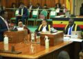 Hon. Wilson Kajwengye (L) speaking during the Committee of the Whole House on Tuesday 23 April 2024. Speaker, Anita Among (C) and a staff of Parliament (R) are at the Clerk’s Table