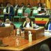 Hon. Wilson Kajwengye (L) speaking during the Committee of the Whole House on Tuesday 23 April 2024. Speaker, Anita Among (C) and a staff of Parliament (R) are at the Clerk’s Table